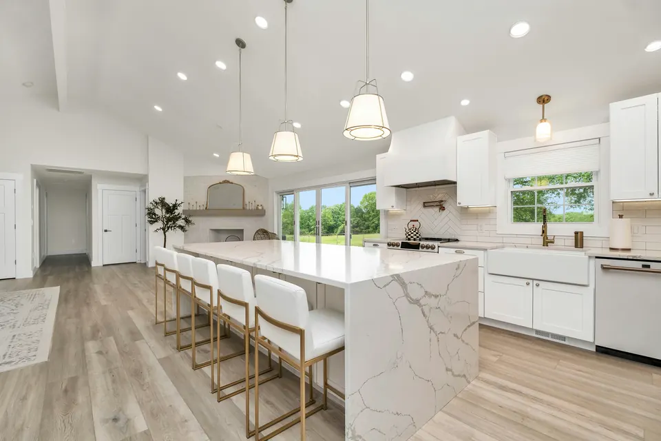 Open-plan kitchen with a long marble island and six stools, after the work