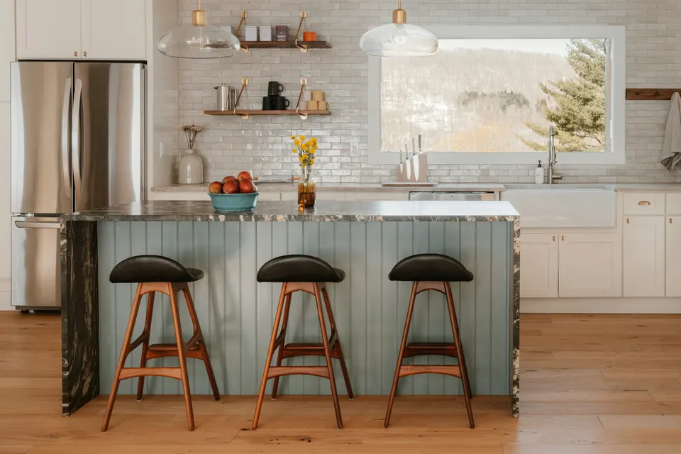 Kitchen island with three bar stools and a farmhouse sink, after the work