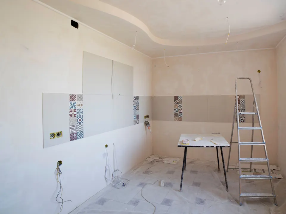 A kitchen under renovation, with bare wires on the walls and a stepladder
